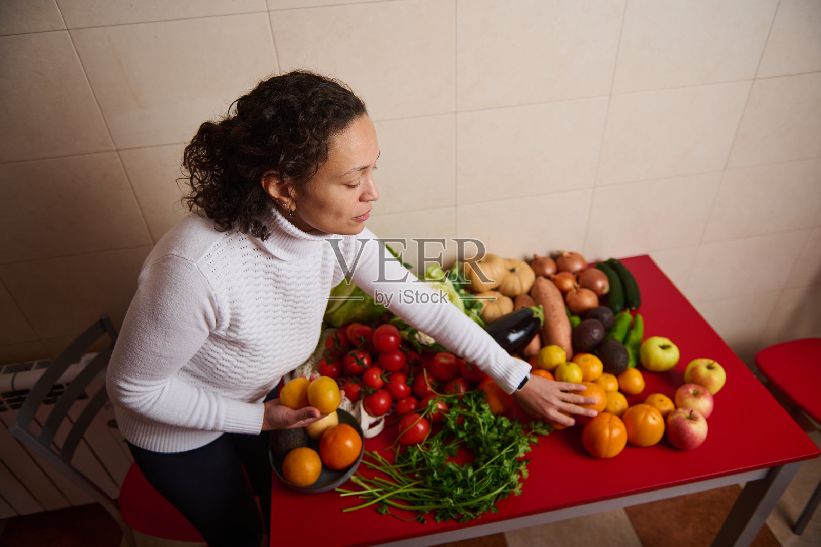 女子在红色桌子上丰盛的集市上挑选新鲜农产品照片摄影图片