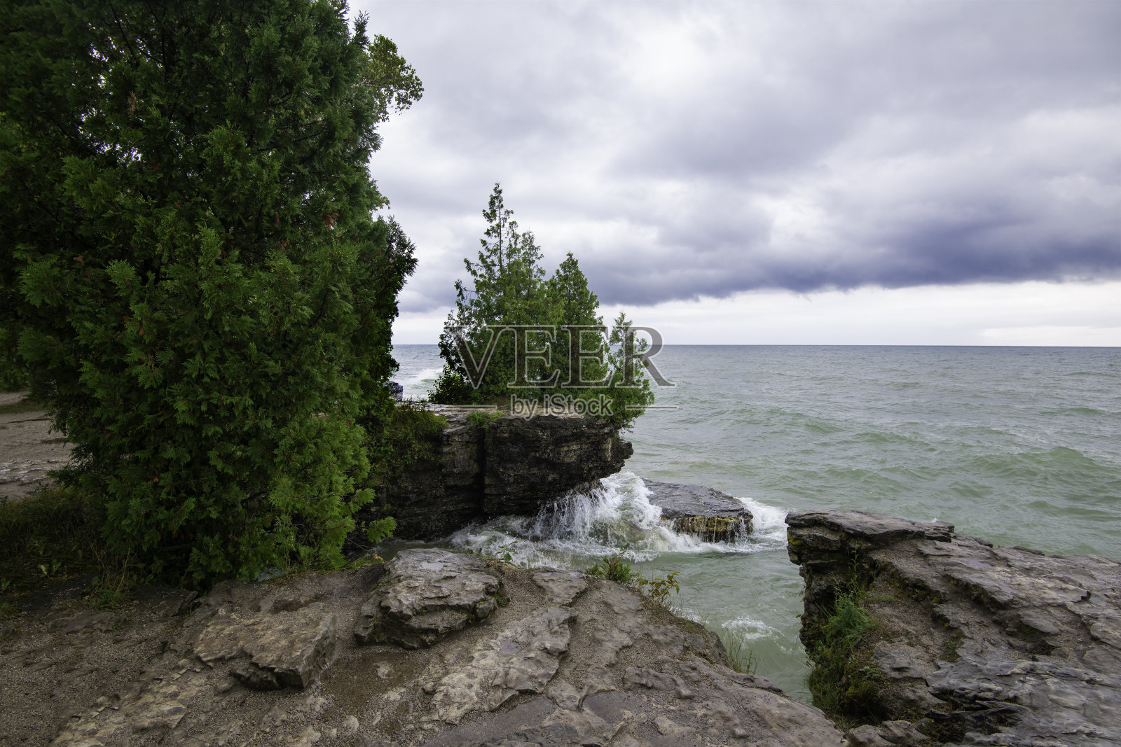 在阴天探索密歇根湖洞穴公园的风景,海浪拍打着岩石海岸照片摄影图片