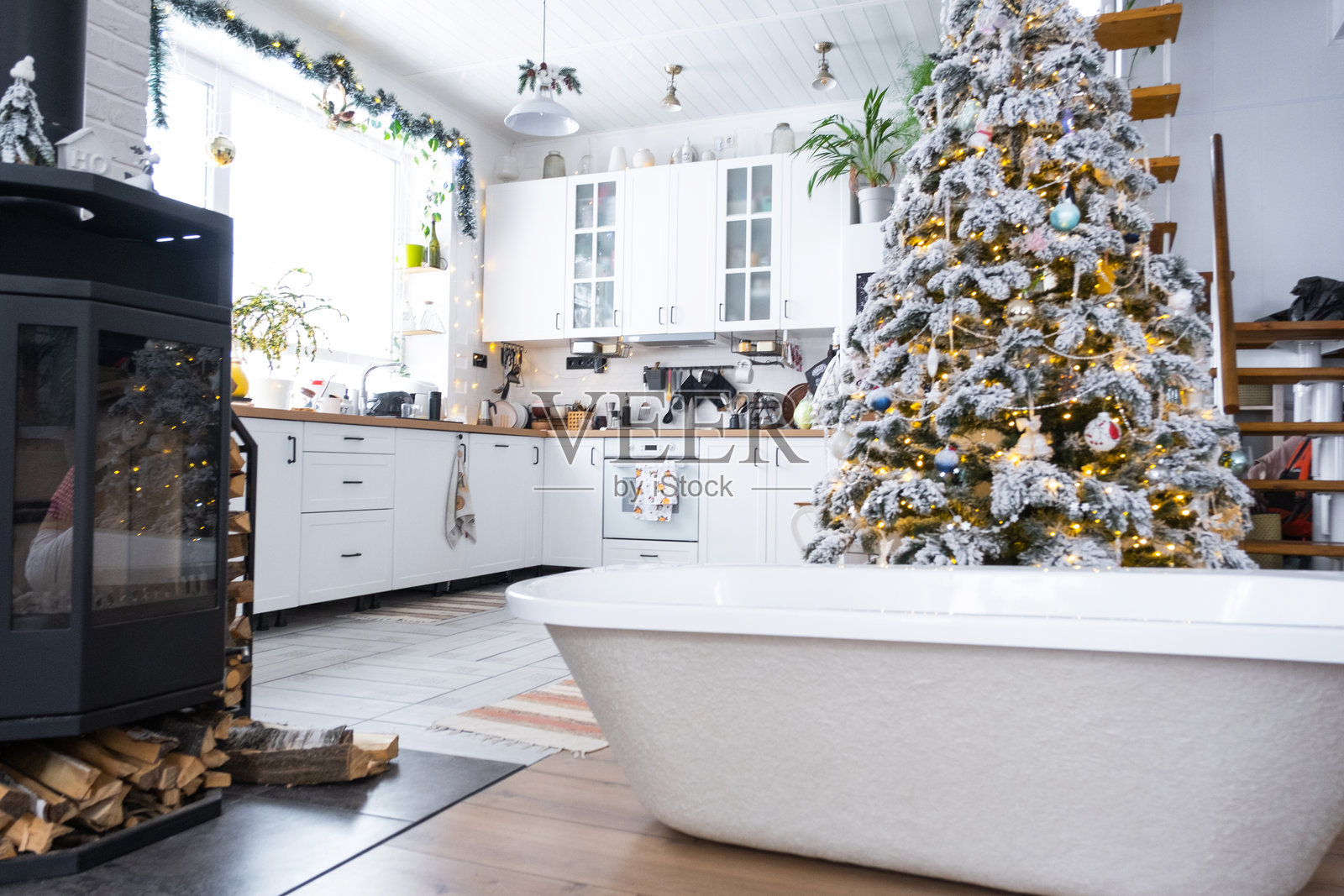 节日圣诞树下的新浴缸,作为新年礼物,摆放在装饰精美的白色现代厨房内。室内翻新与设计、施工及家居装修。照片摄影图片