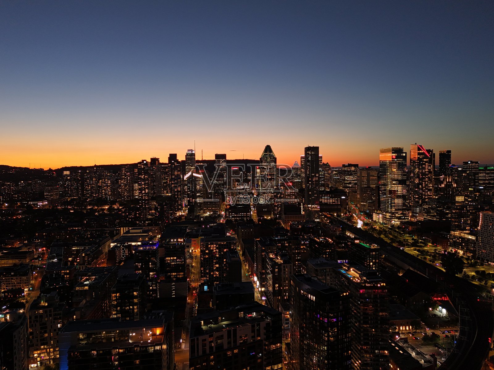 蒙特利尔市中心和格里芬镇的城市天际线在黄昏时分,城市灯光倒映在水面上。照片摄影图片