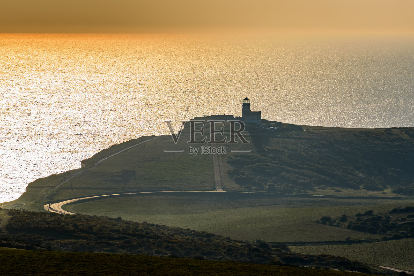 橙色日落天空下的悬崖灯塔照片摄影图片