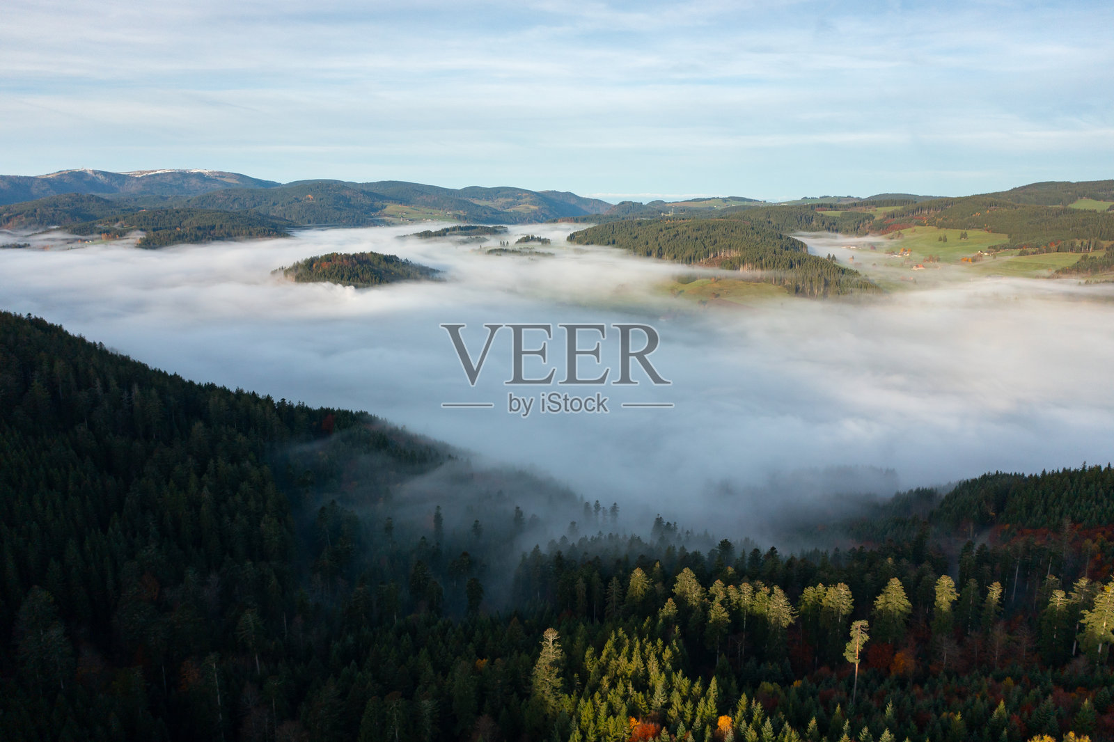 航拍无人机照片,展现了被秋季森林覆盖的山隘和飘渺的雾层照片摄影图片