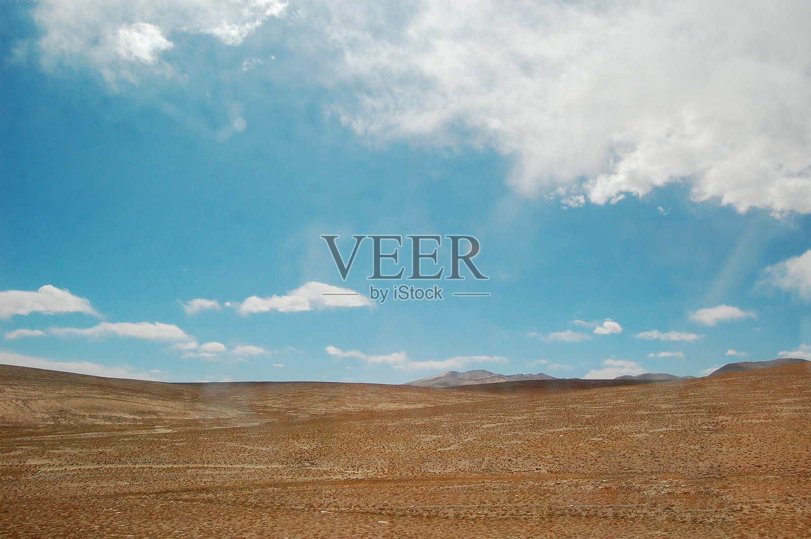 晴朗的蓝天下,点缀着几朵白云的辽阔干旱平原照片摄影图片