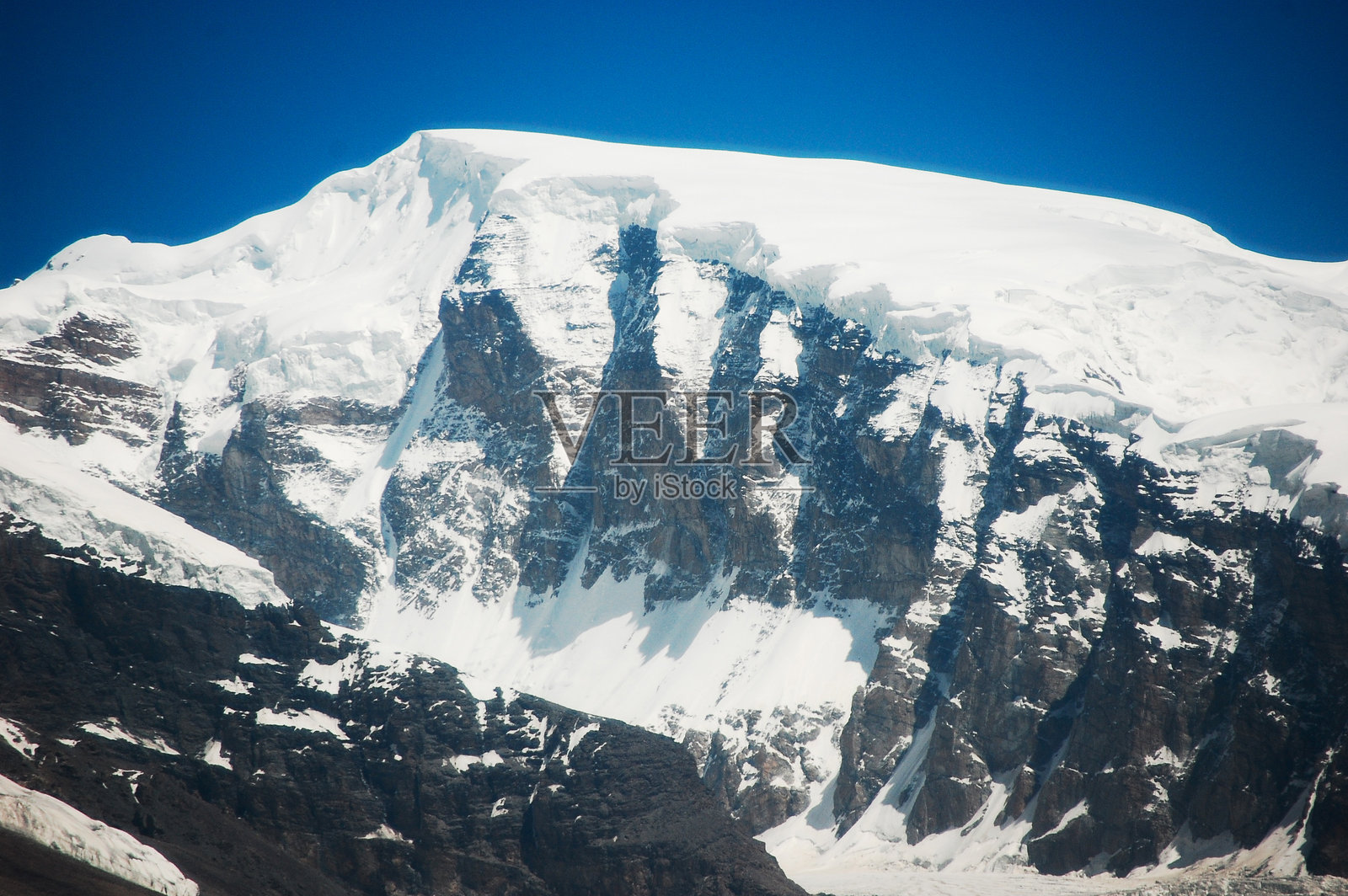 晴朗蓝天下白雪皑皑的雄伟山峰照片摄影图片