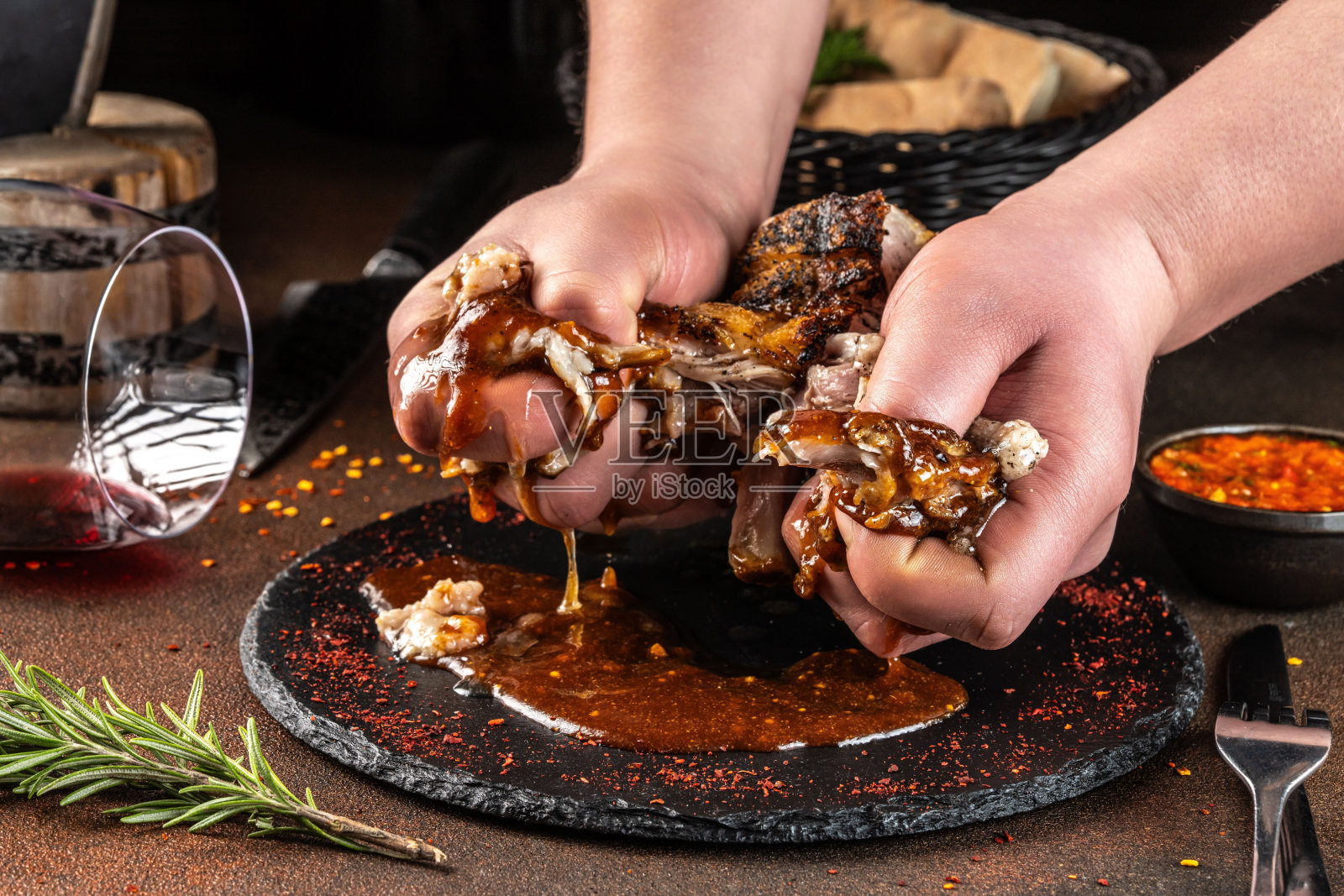 用手撕下烤肉酱猪肋排,放在石板盘上。照片摄影图片