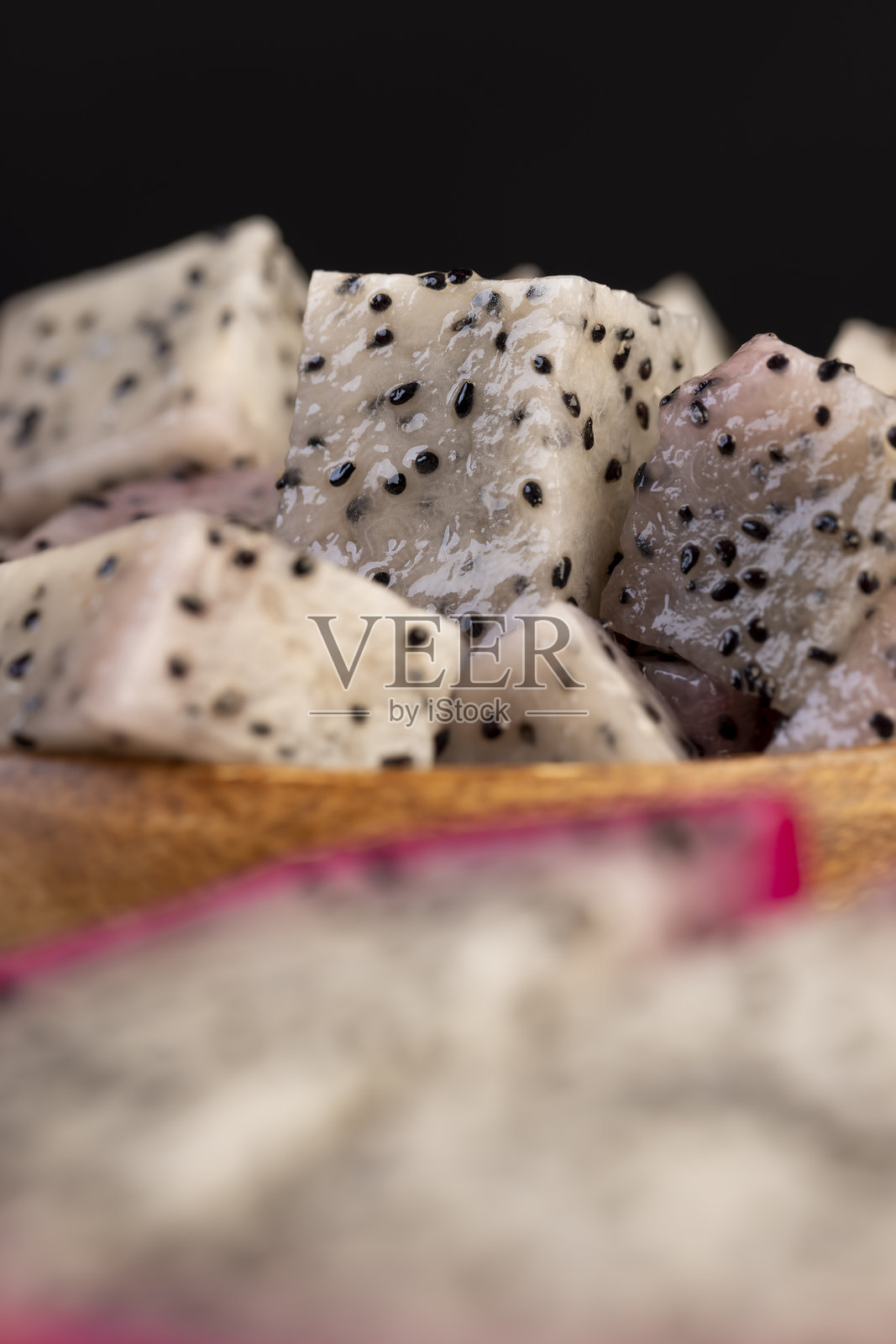 切成小块的成熟红心火龙果,里面有很多小黑籽和白色的软肉,甜美的熟龙果切成两半,切成小方块,带有黑色小籽和浅色果肉照片摄影图片