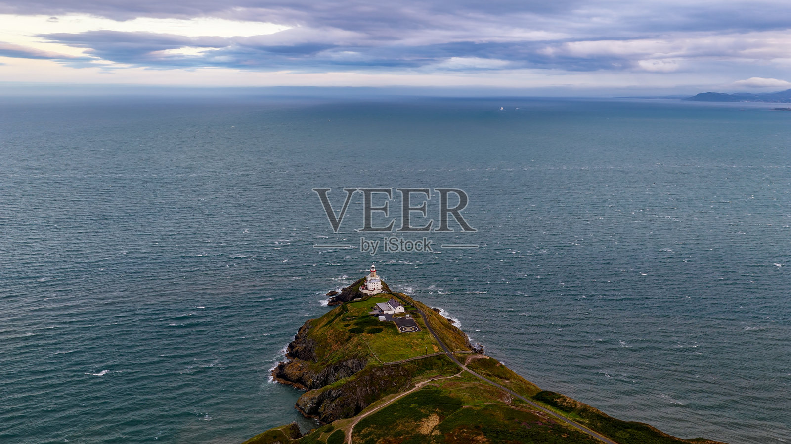 从空中俯瞰都柏林霍斯头半岛的贝利灯塔,一座位于戏剧性海崖上的历史悠久的海岸灯塔,享有全景海景,是航海遗产和旅游业的导航与旅行概念。照片摄影图片