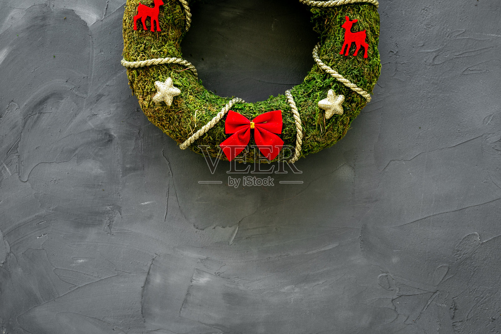 墙上用绿色苔藓制成的圣诞花环,带有红色蝴蝶结。新年手工装饰照片摄影图片