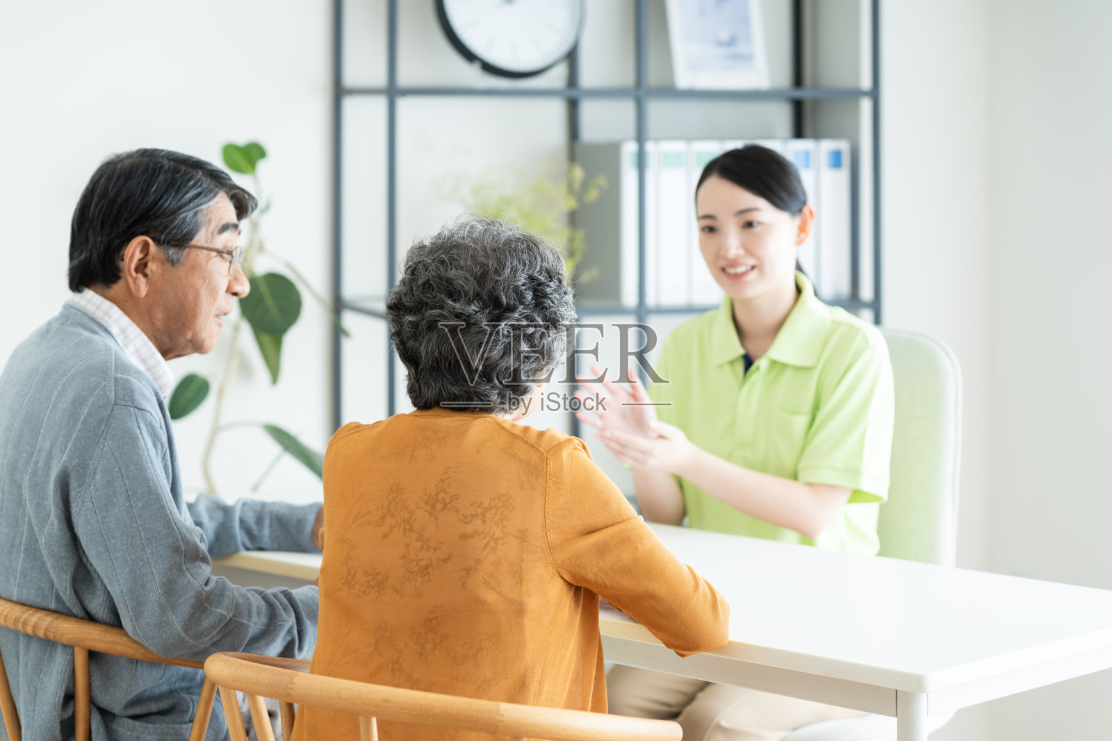 一位年轻的女看护者正在向一对老年夫妇解释情况照片摄影图片