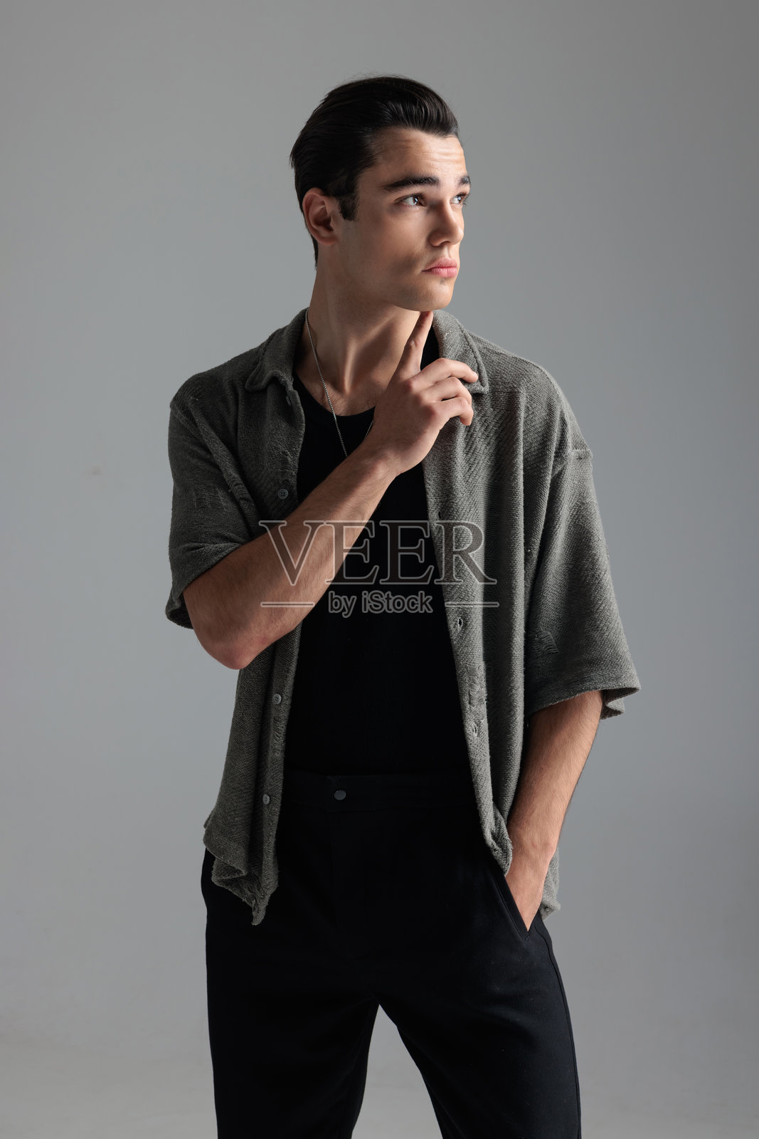 性感的年轻男子穿着灰色开衫,侧目思索照片摄影图片