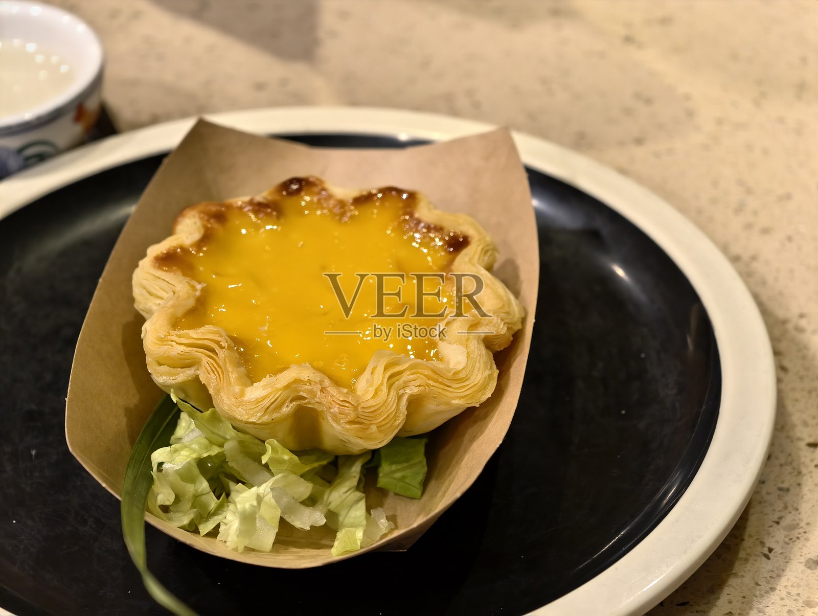 黑盘上的脆皮蛋挞配生菜照片摄影图片