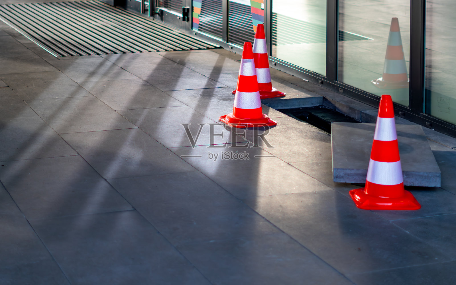 楼体前方技术区域地板上暴露的电气连接器旁放置着橙色警示锥照片摄影图片