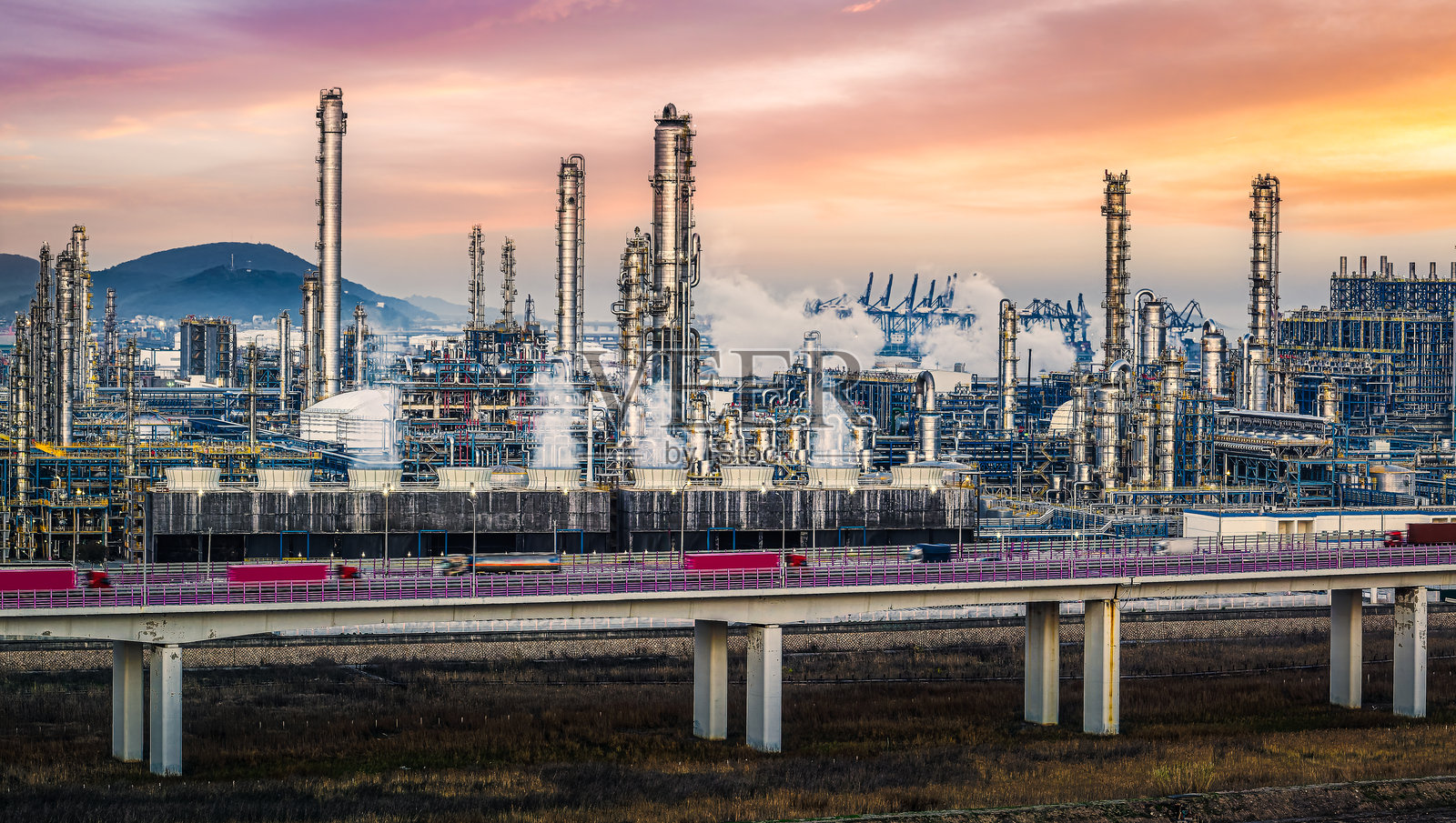 日落时分,工业区内大型炼油厂和化工厂的烟囱冒着浓烟,呈现出壮丽的景象。照片摄影图片