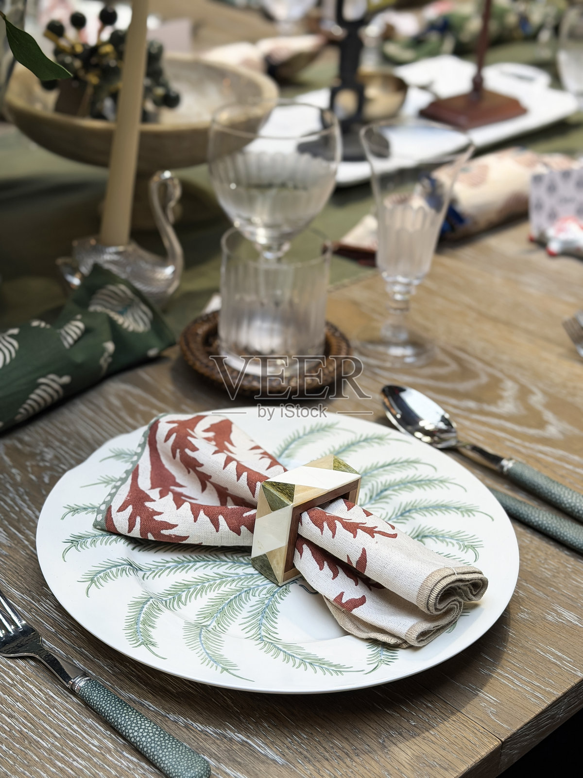 一张优雅的圣诞晚宴餐桌布置图,包括协调的餐垫、盘子、碟子和整齐折叠的餐巾。照片摄影图片