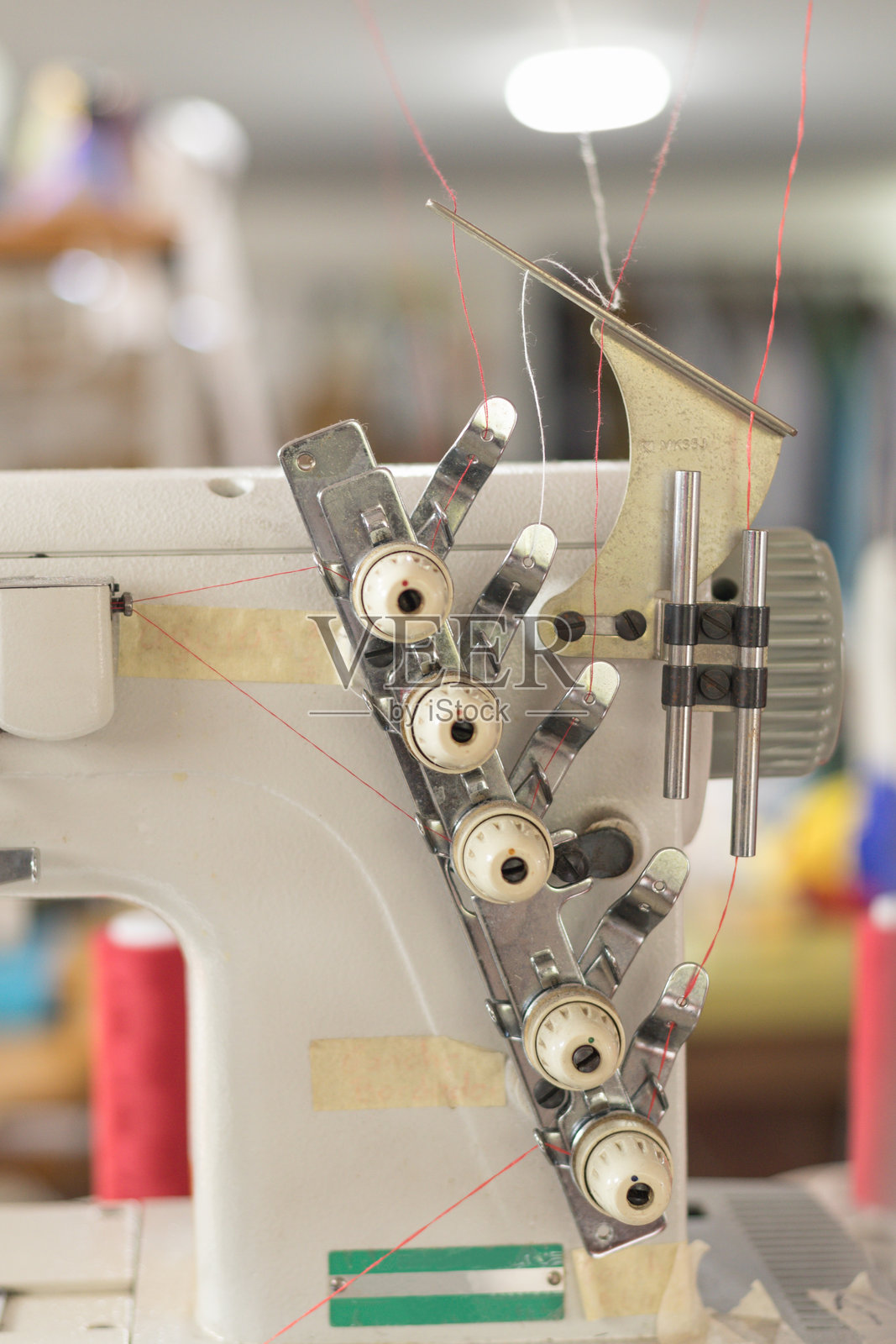 工业缝纫机的精细调线张力旋钮和红色线,准备在车间环境中进行纺织品制造照片摄影图片