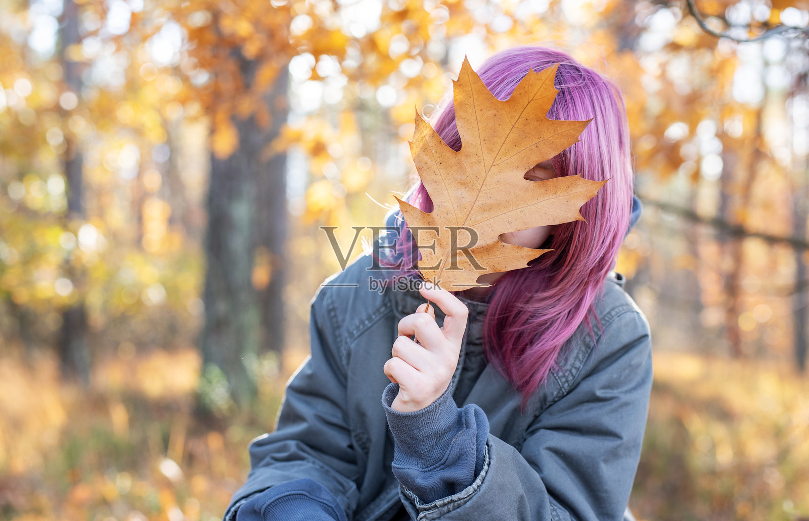 年轻女子用秋叶遮住脸照片摄影图片