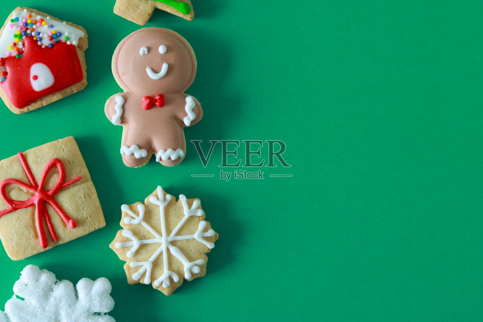 节日圣诞饼干和雪花,背景为绿色,布局整洁,留有充足的复制空间,可用于节日信息或设计元素。照片摄影图片