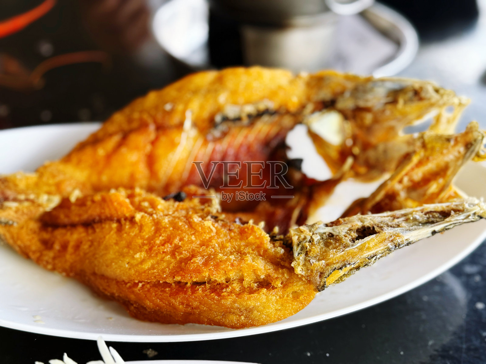 黑底白盘上的辣酱炸鱼照片摄影图片