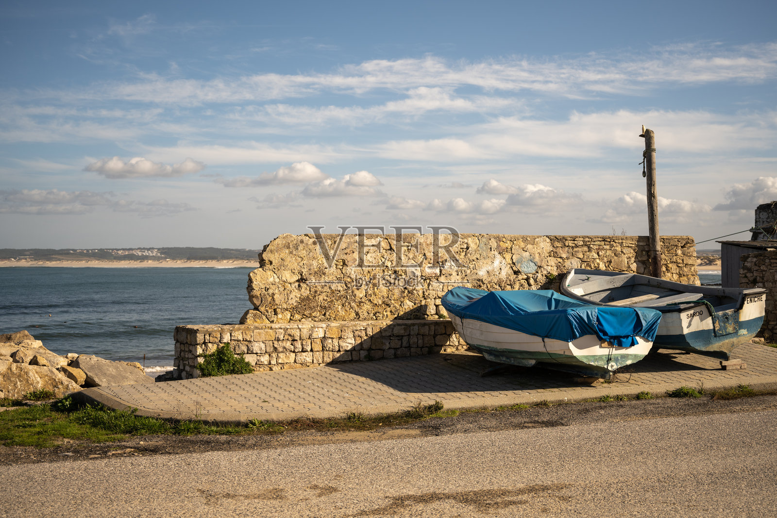 葡萄牙佩尼切,渔船停靠在石头墙边,眺望着沙质海岸线照片摄影图片