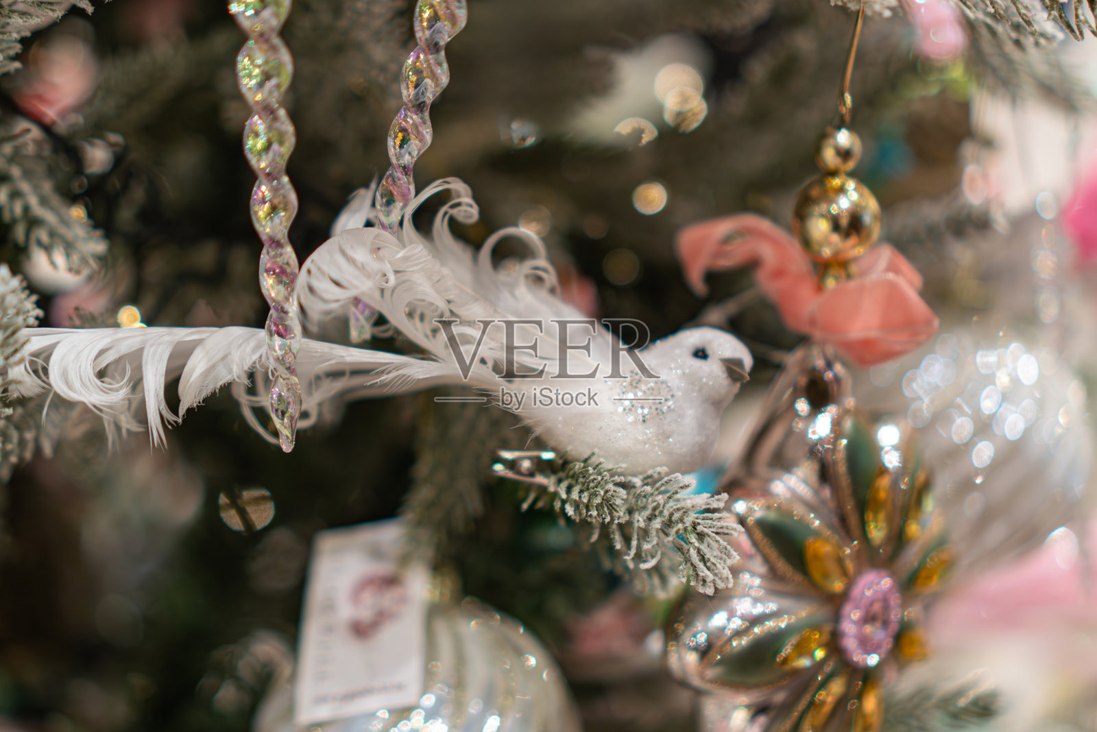 一棵位于中心的真松圣诞树,装饰有大小不一的羽毛状和圆形饰品,其中还包括一只栖息的鸟形玩偶,同时为新年和圣诞节进行了装饰。照片摄影图片