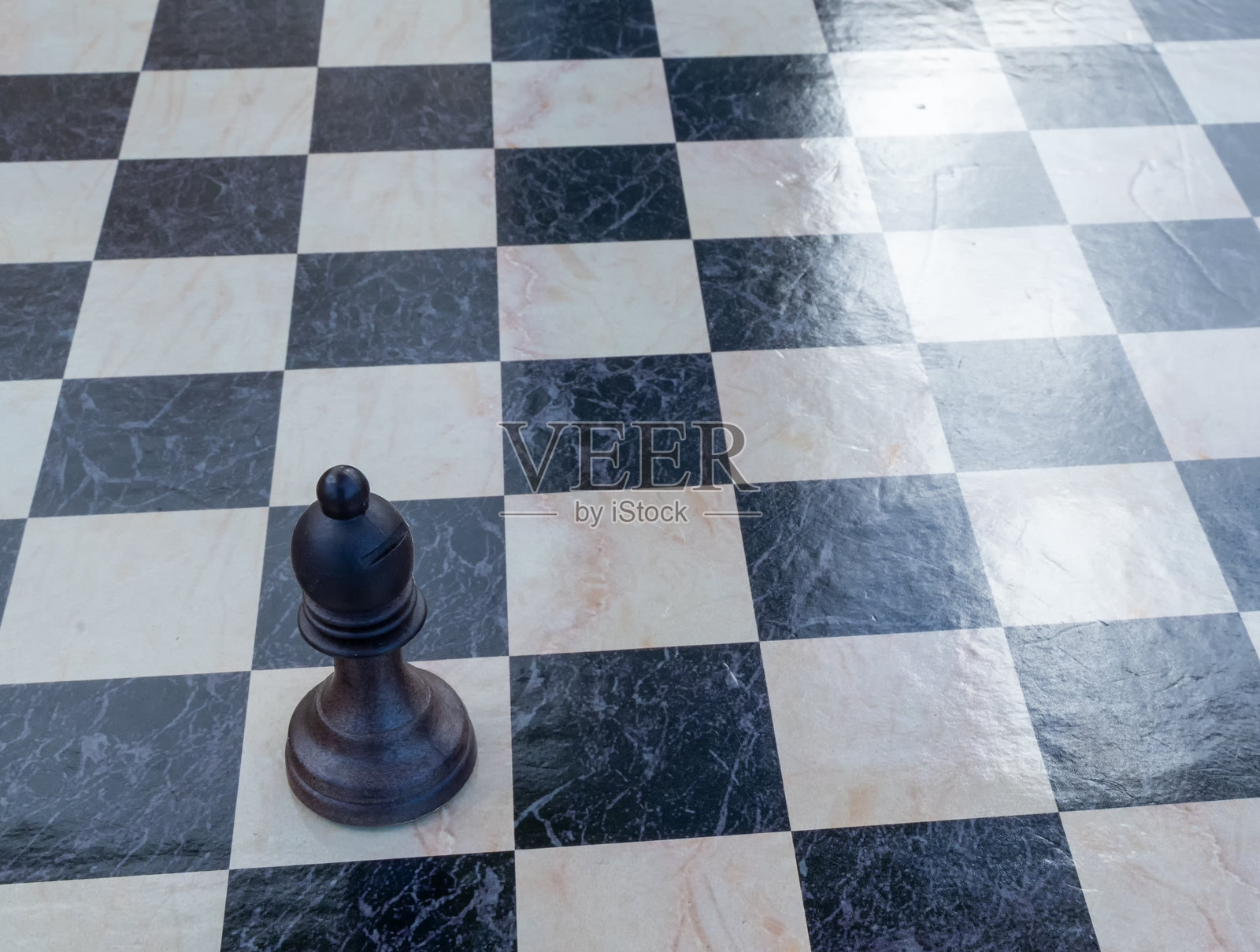 一个国际象棋的象,独自站在一个带有黑白大理石纹理的棋盘上照片摄影图片