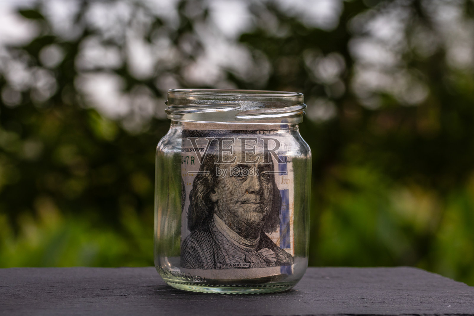 美元钞票存入玻璃罐。消费与经济。商业、小费、金融、储蓄、银行与人物概念照片摄影图片