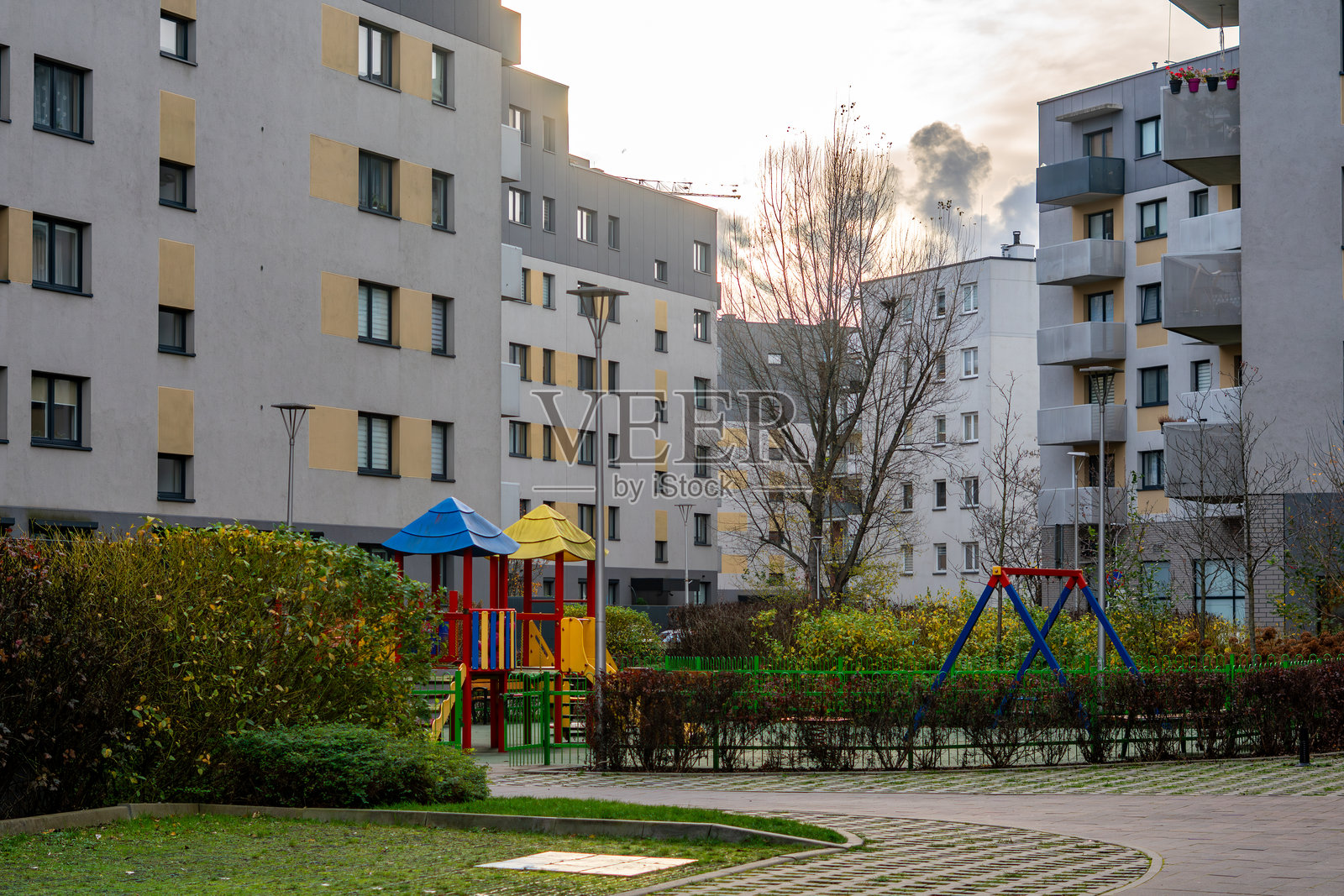 现代住宅区,带有一个被灌木丛和住宅楼环绕的游乐场,为居民创造了一个有组织的娱乐空间照片摄影图片