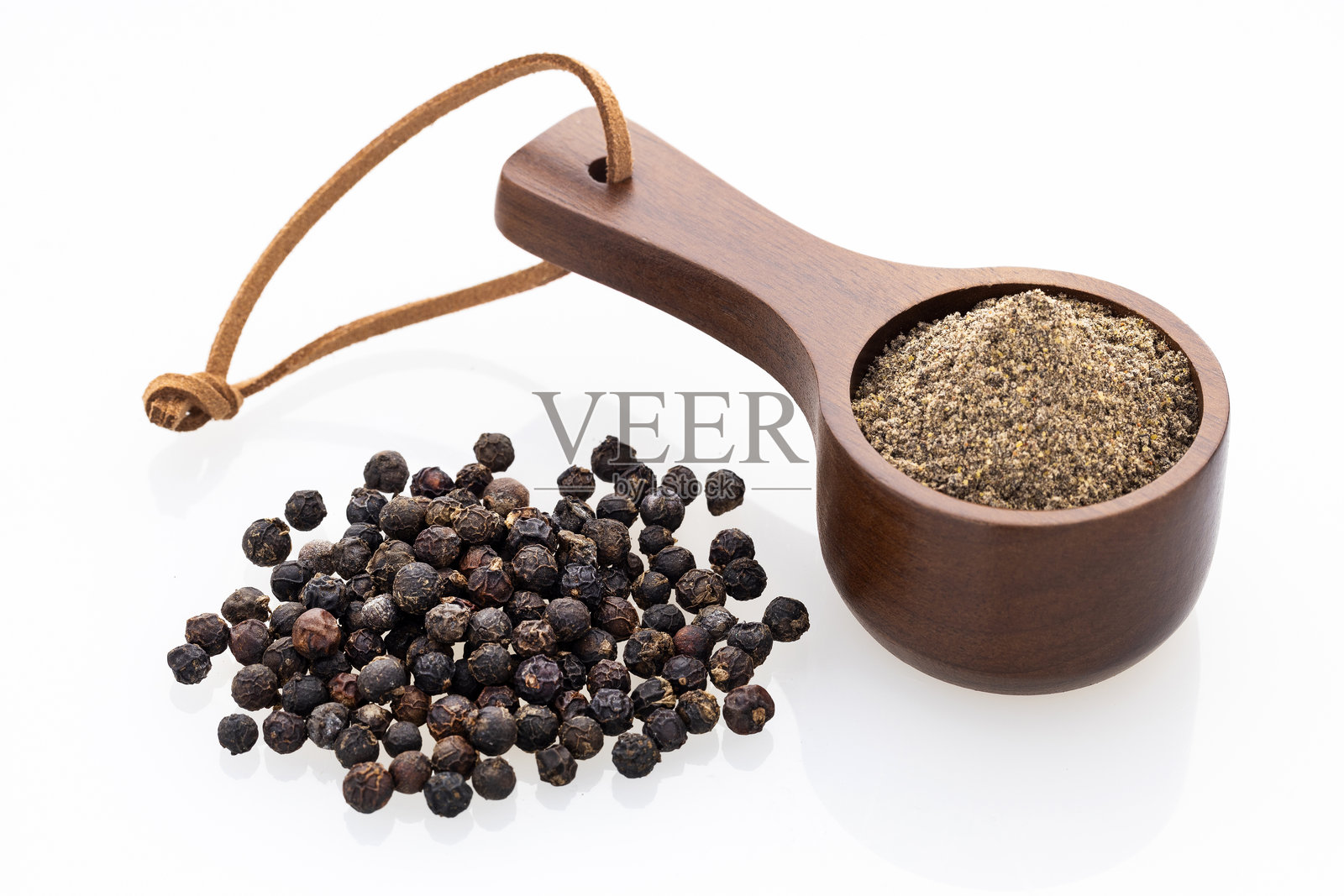 白色背景下,量勺中的黑胡椒粉和整粒胡椒照片摄影图片