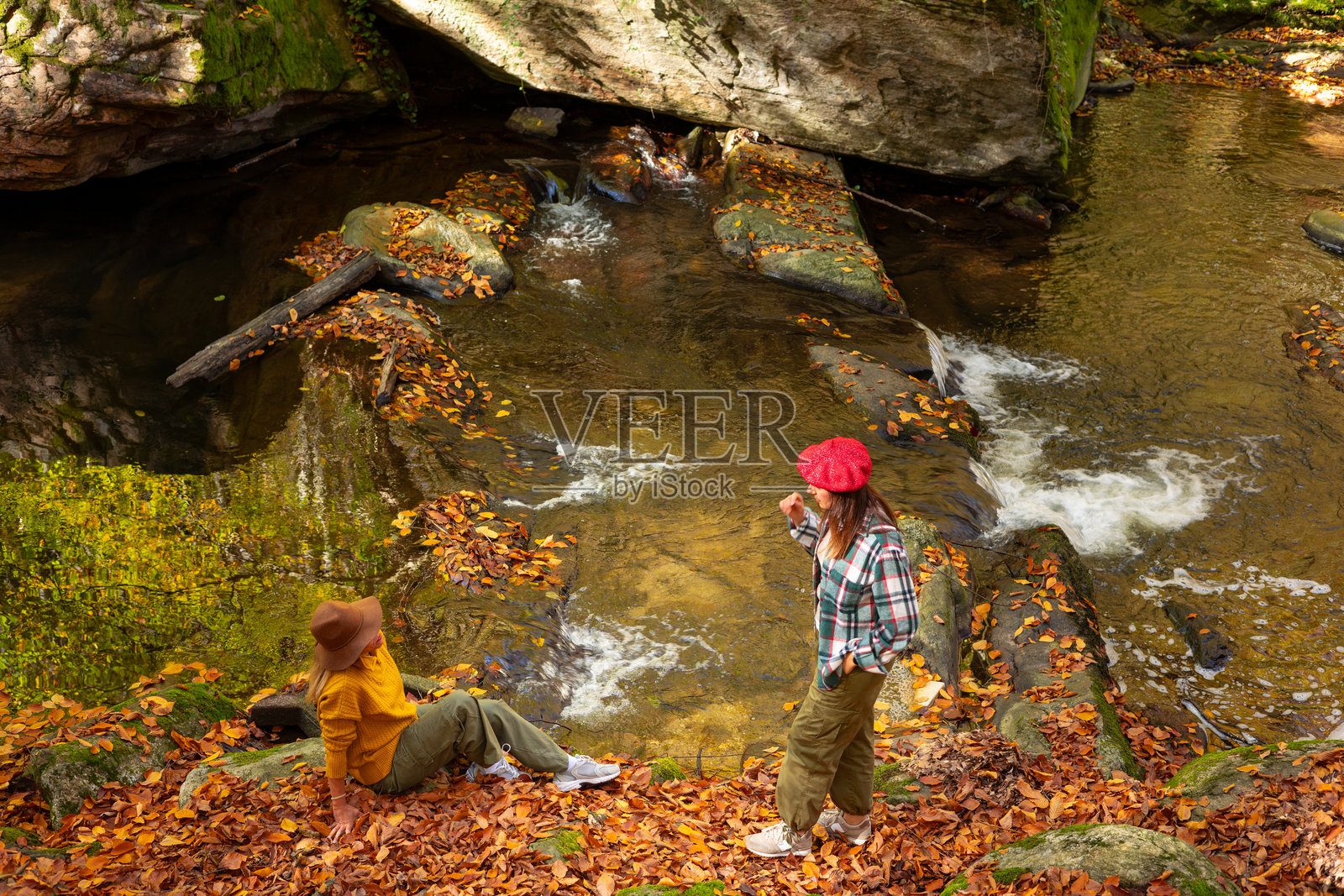 两位女士在风景优美的河边享受秋季森林徒步照片摄影图片