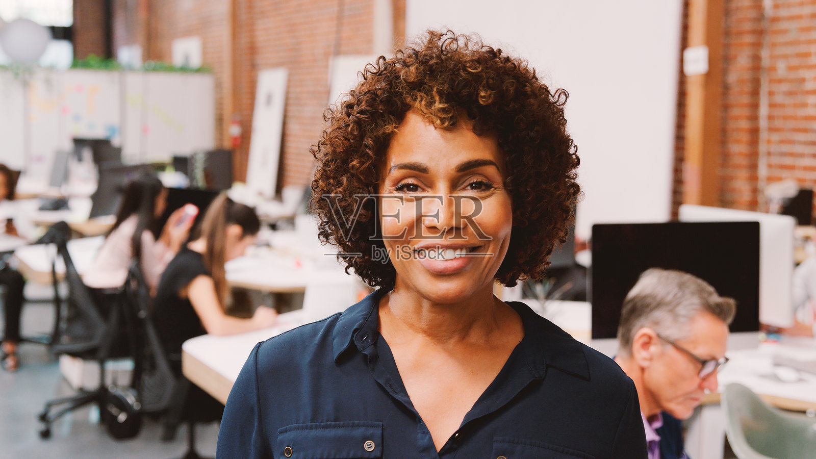 职业女性在现代办公室砖墙前微笑照片摄影图片