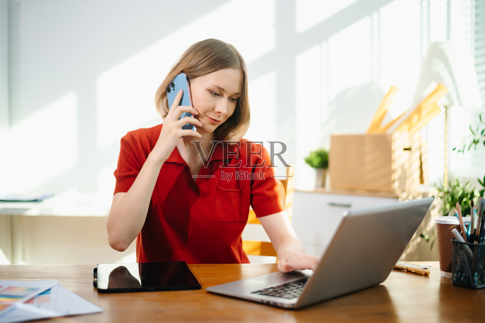 一位白人女性在她明亮的家庭办公室里用智能手机交谈。非常适合沟通、远程工作。照片摄影图片