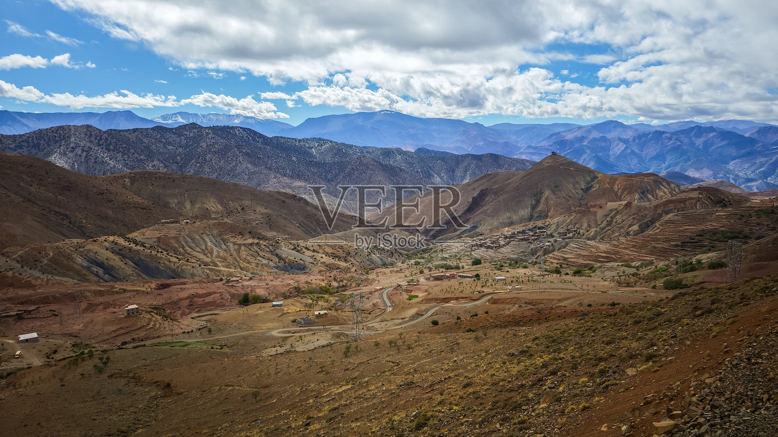 摩洛哥干旱梯田山谷和高耸山脉的戏剧性全景背景,散布着伯ber村庄,天空广阔多云照片摄影图片