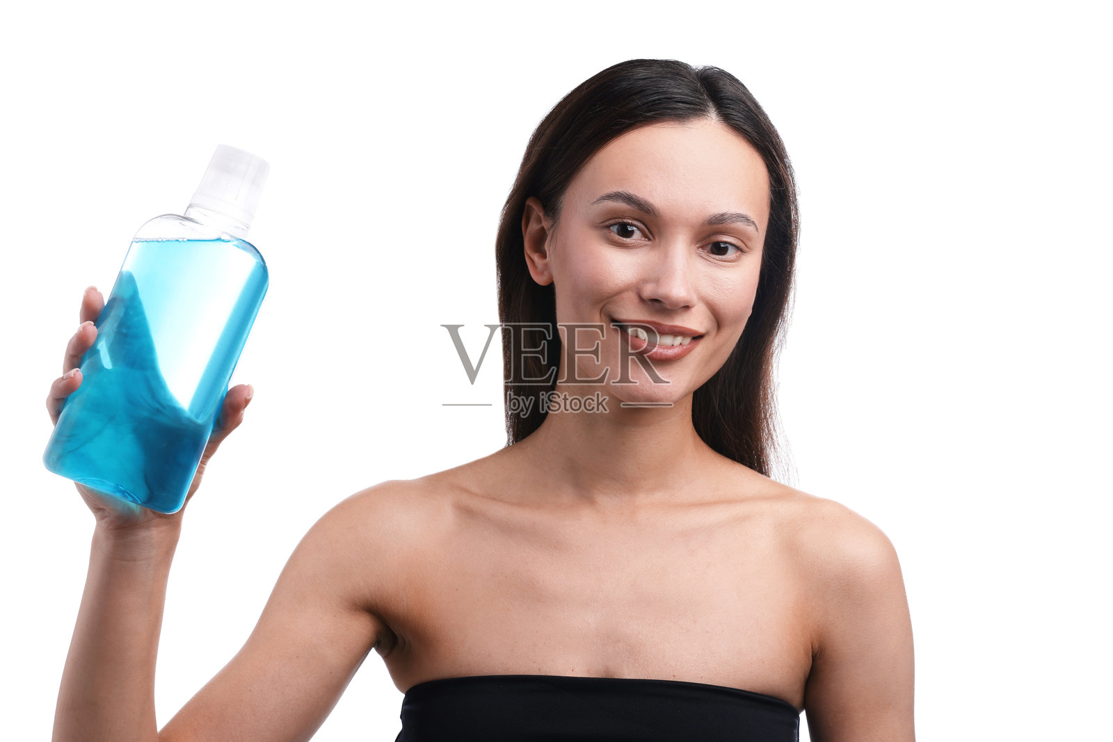 背景为白色的年轻女子,手持漱口水瓶,面带微笑,注重口腔卫生。照片摄影图片