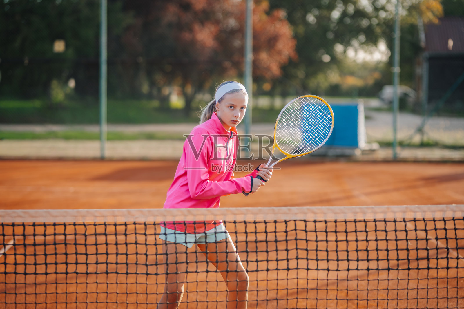 年轻女孩在红土球场上打网球照片摄影图片