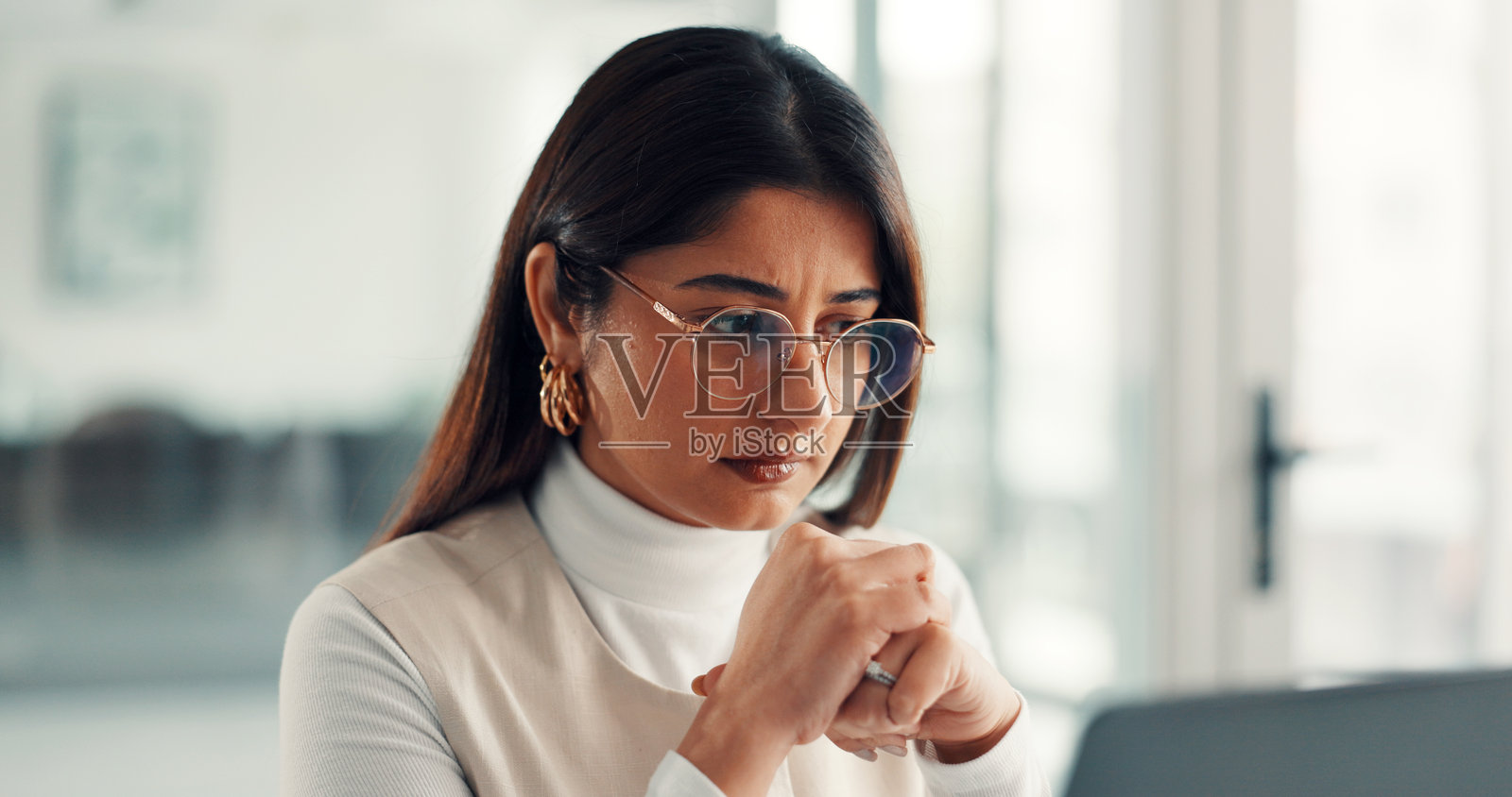 女性作家在创业公司因项目管理而感到压力,她在办公室对着电脑审阅文件或戴着眼镜。这位媒体顾问在电脑上查看提案,在创意机构因文章内容感到困惑或有所启发。照片摄影图片