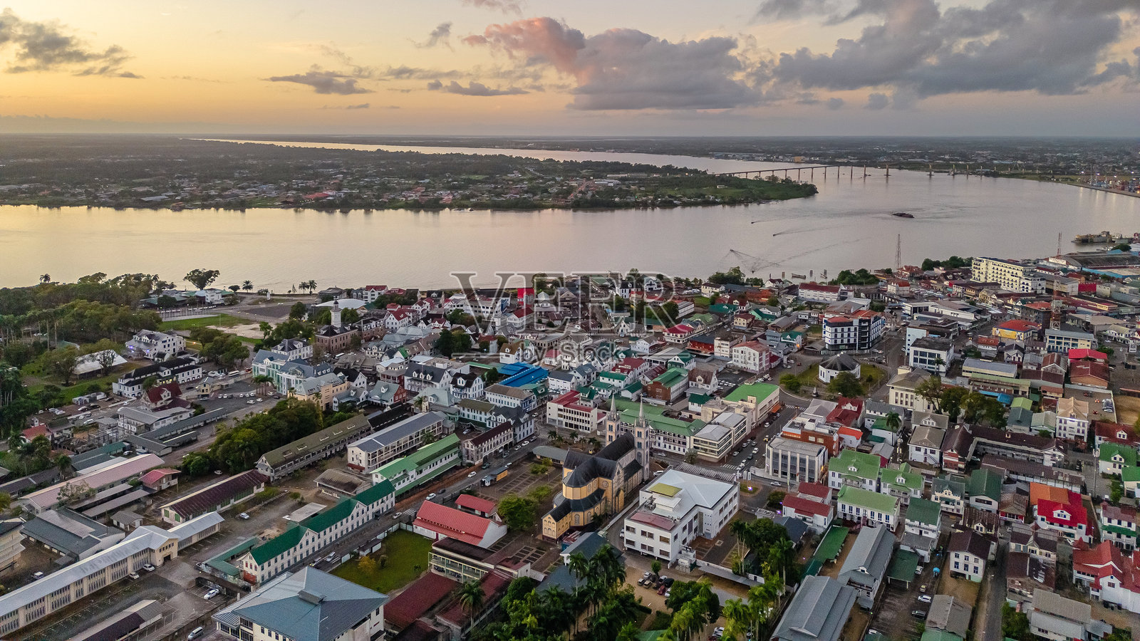 苏里南帕拉马里博的空中城市景观,展示了历史悠久的圣彼得保罗大教堂和周围的殖民时期建筑,在河畔沐浴在美丽的日出光辉中照片摄影图片