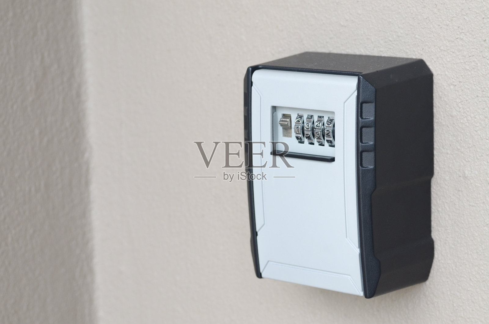 授权进入系统:一个带有1234密码的钥匙锁箱固定在浅色墙壁上,象征着受控访问和家庭安全。照片摄影图片
