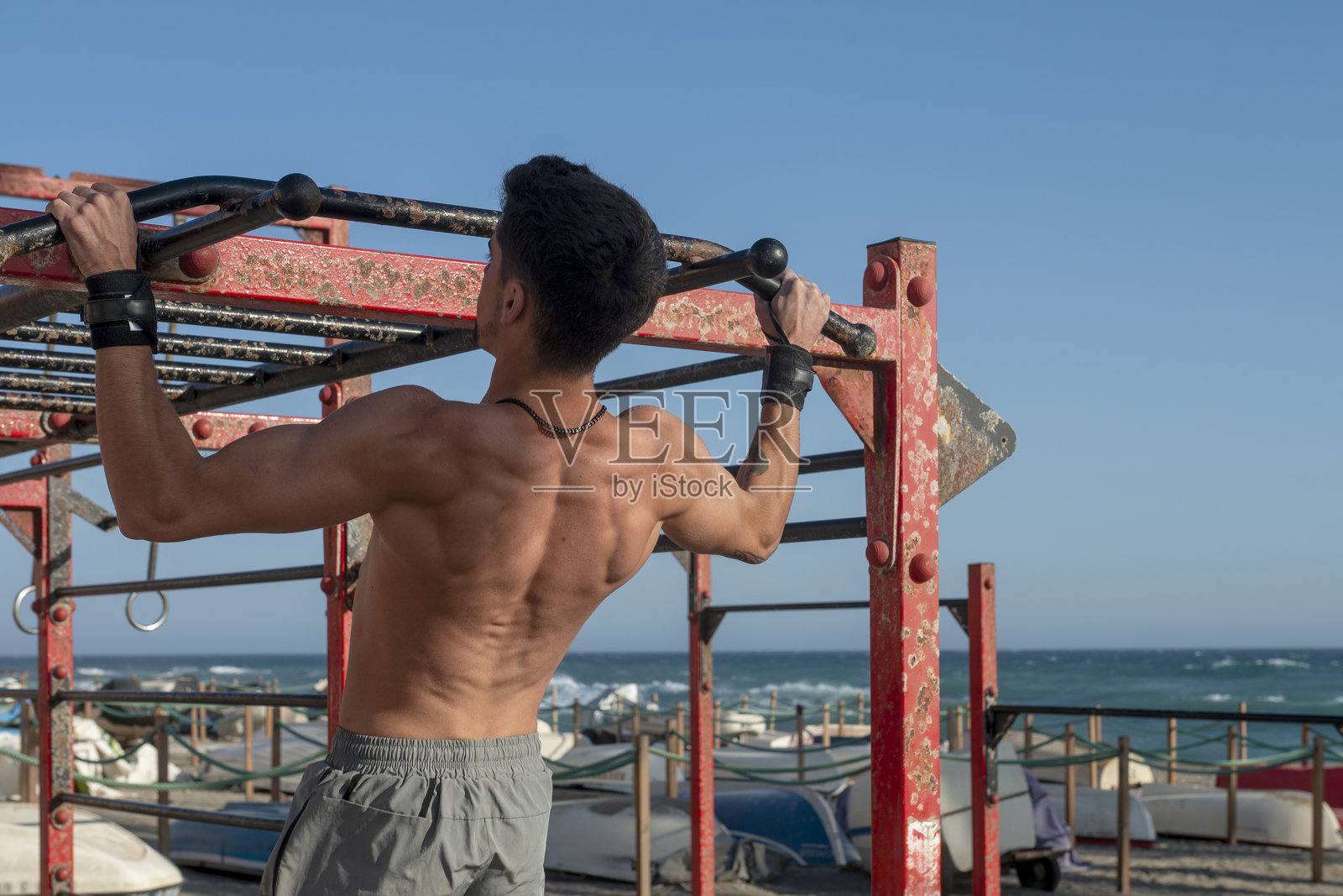 男人在户外利用健身体育器械做引体向上照片摄影图片