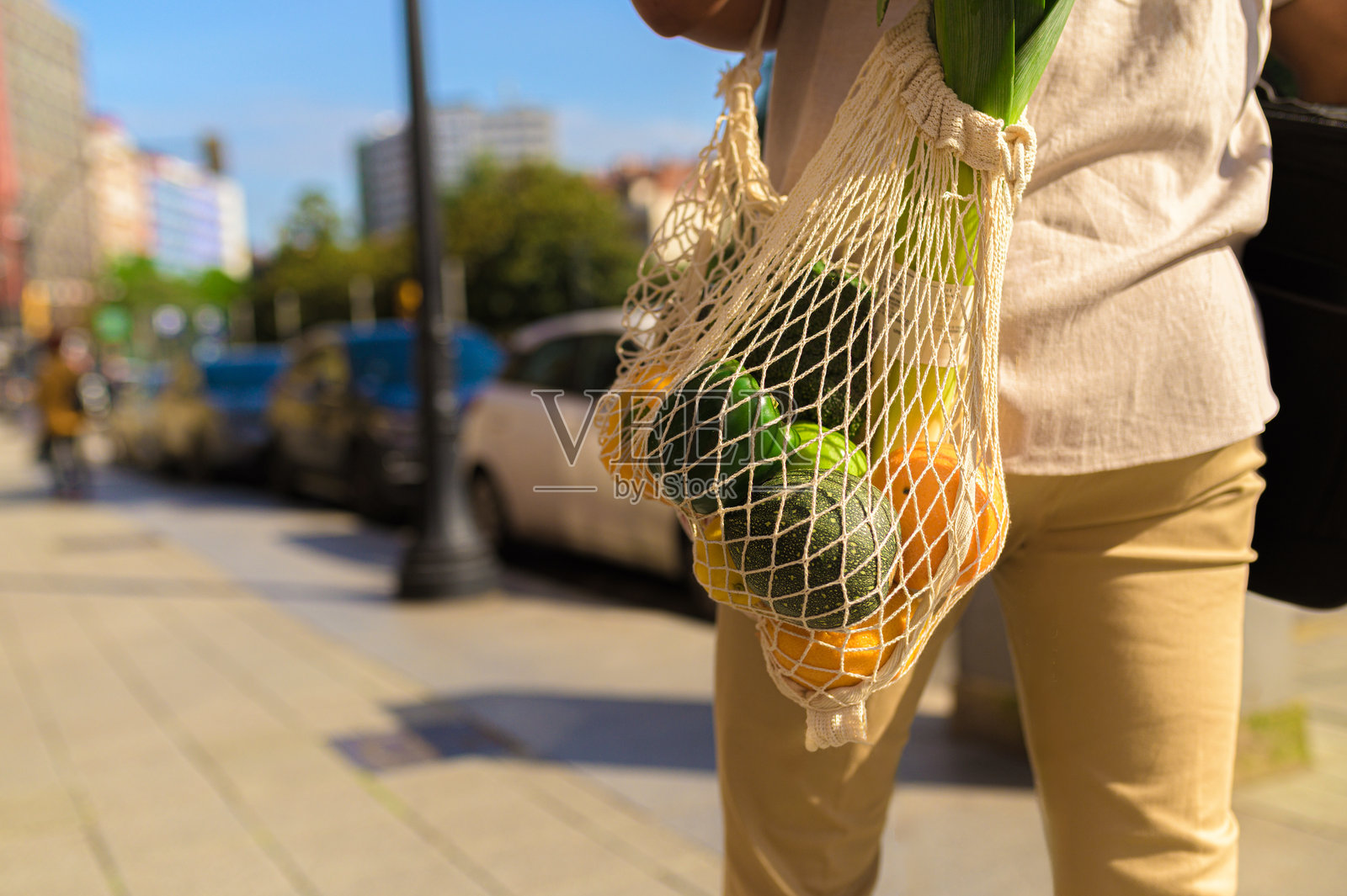 一个人提着装有蔬菜的可重复使用网袋照片摄影图片