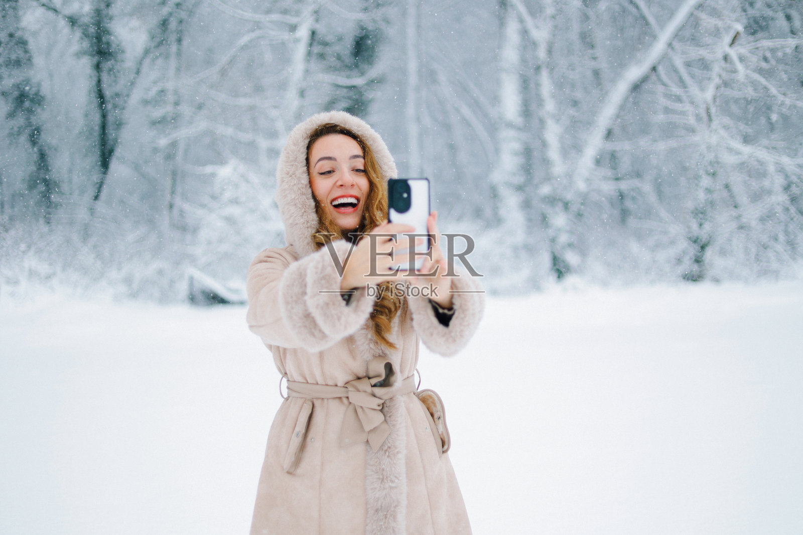一位女士在冬天用智能手机自拍照片摄影图片