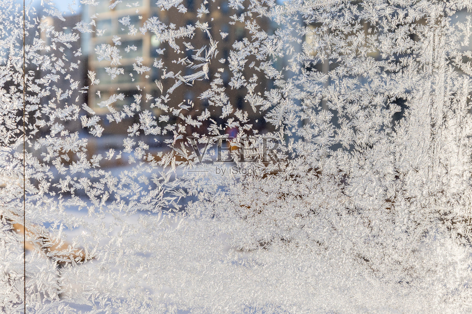 背景虚化的冬季景观,窗户上覆盖着错综复杂的霜花图案。精致的冰晶形成自然的艺术纹理,展现冬日之美。照片摄影图片