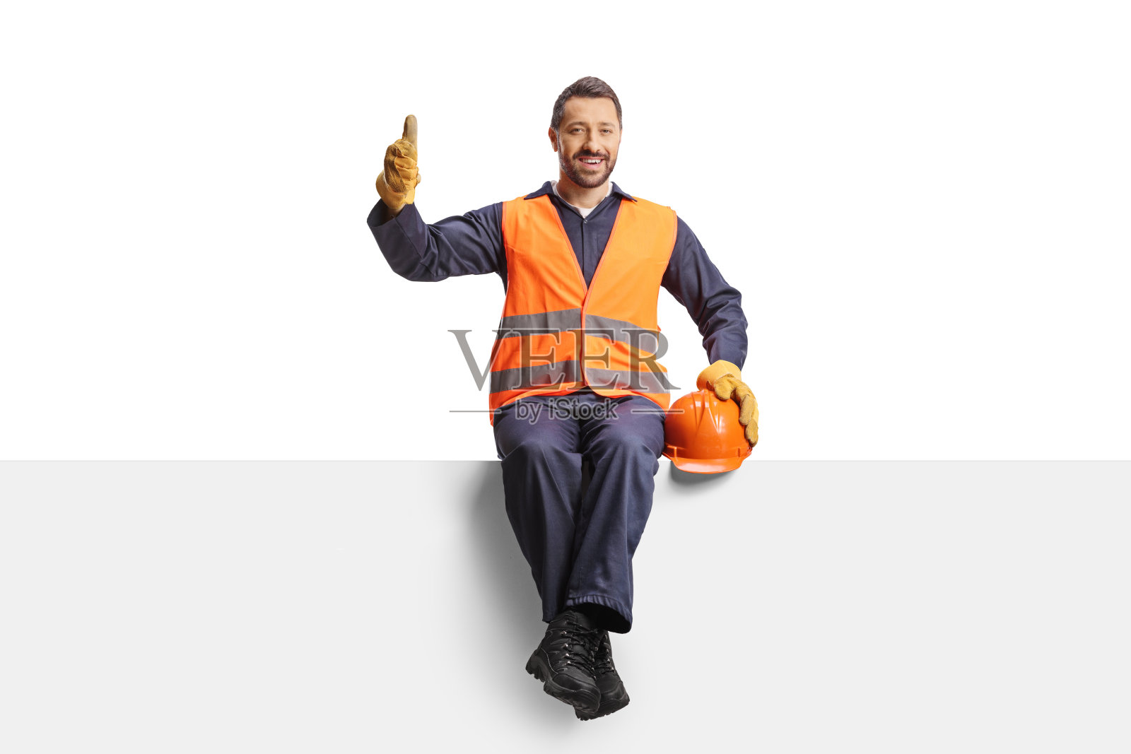 微笑的建筑工人坐在一块板上竖起大拇指照片摄影图片