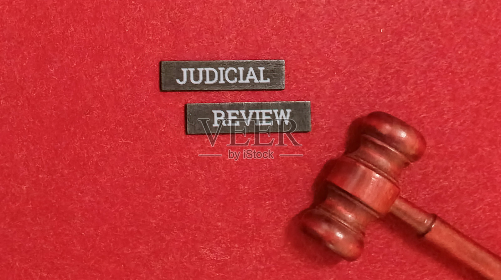 红底背景上的法官木槌和司法审查文本照片摄影图片