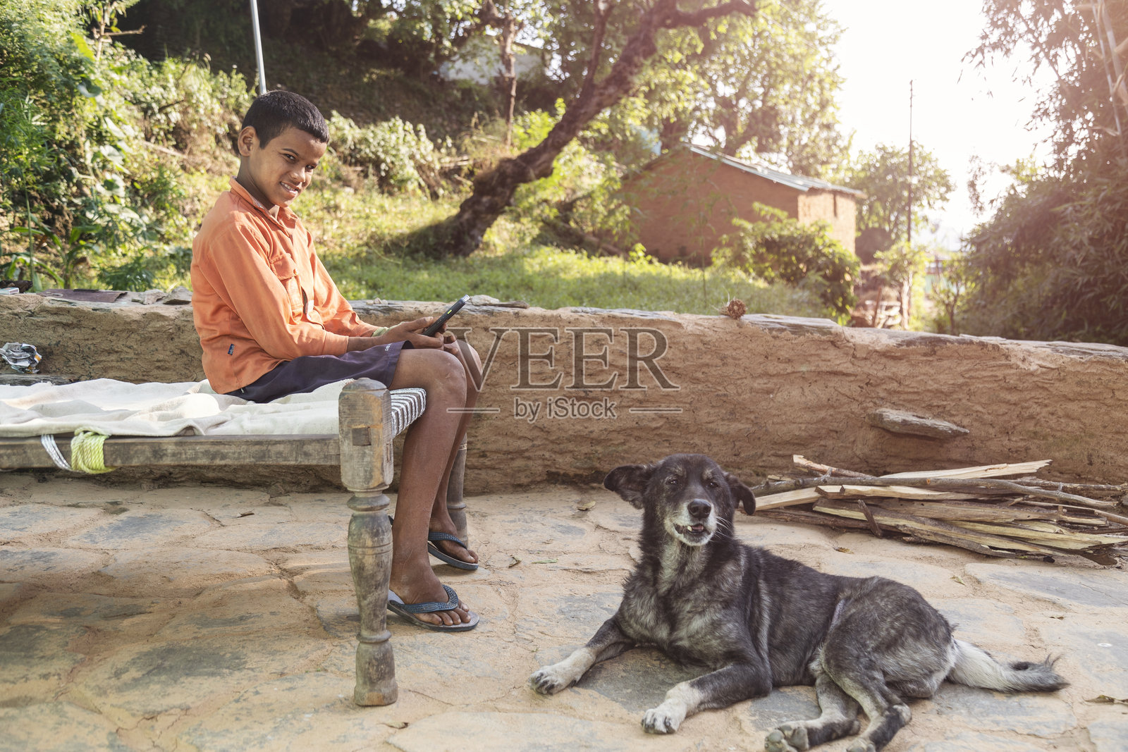 贫困的北阿坎德邦山区,农村男孩与宠物狗一起使用智能手机照片摄影图片