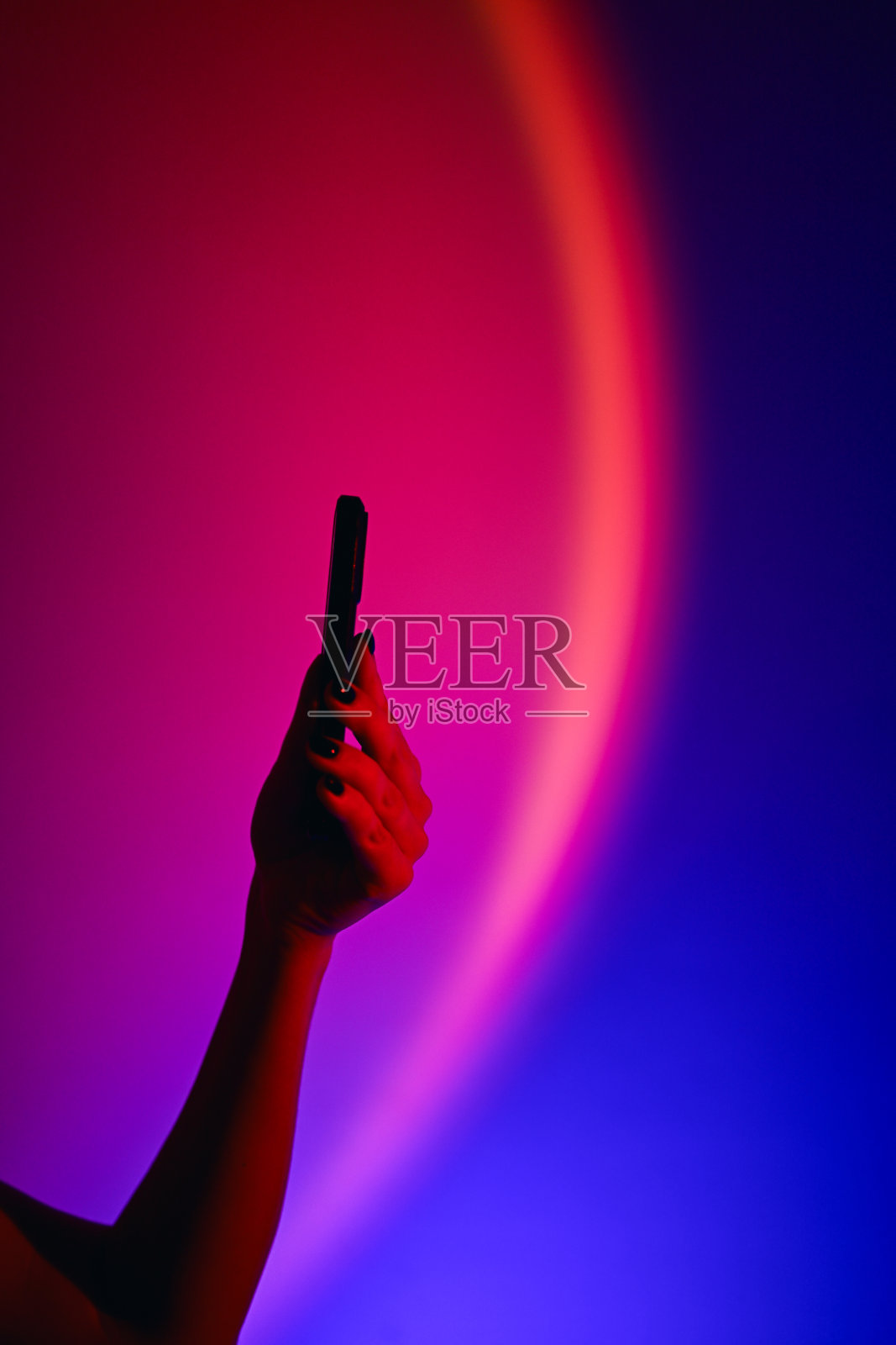 手持智能手机,背景为霓虹渐变色照片摄影图片