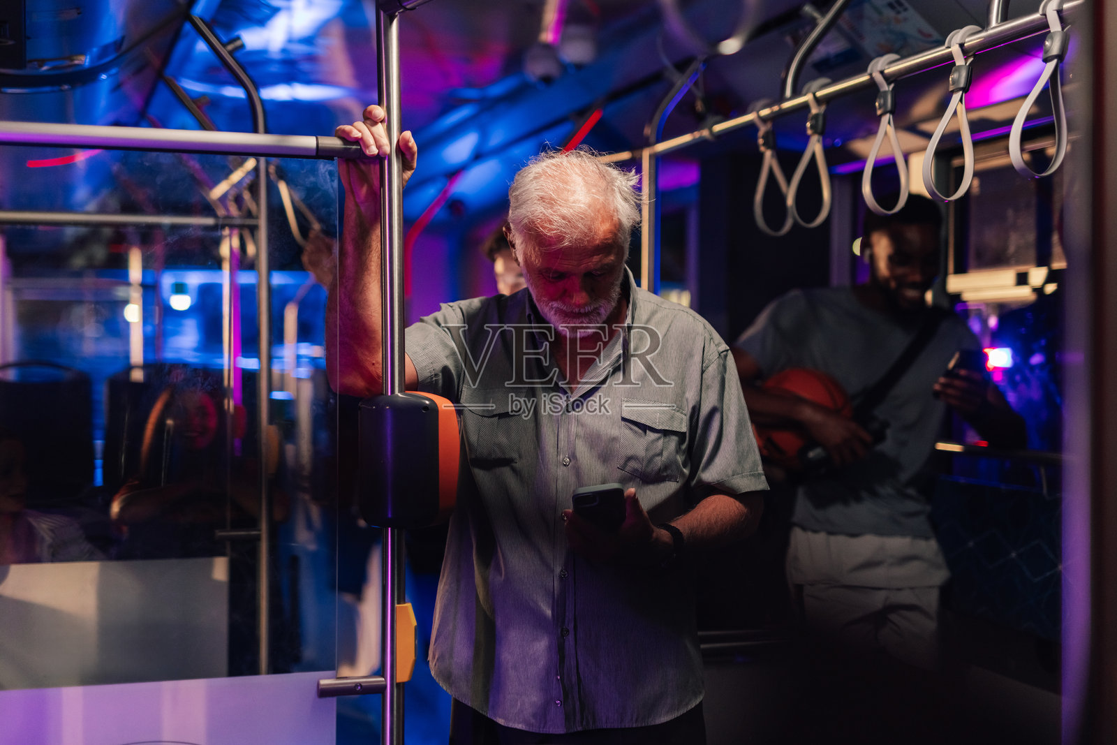 年长乘客在夜间通勤巴士上使用智能手机照片摄影图片