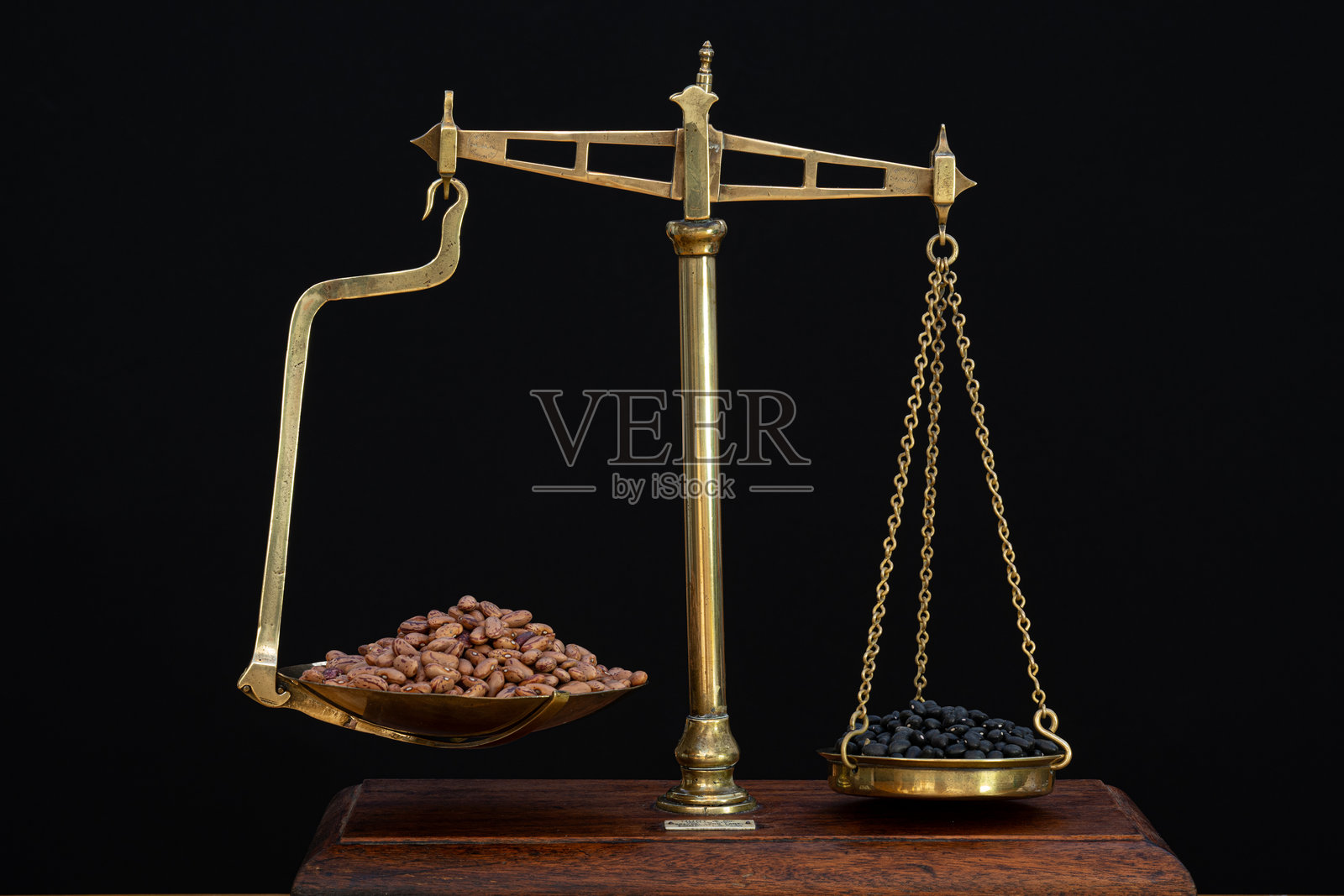 以象征性的方式比较旧黄铜秤上不同颜色豆子的重量照片摄影图片