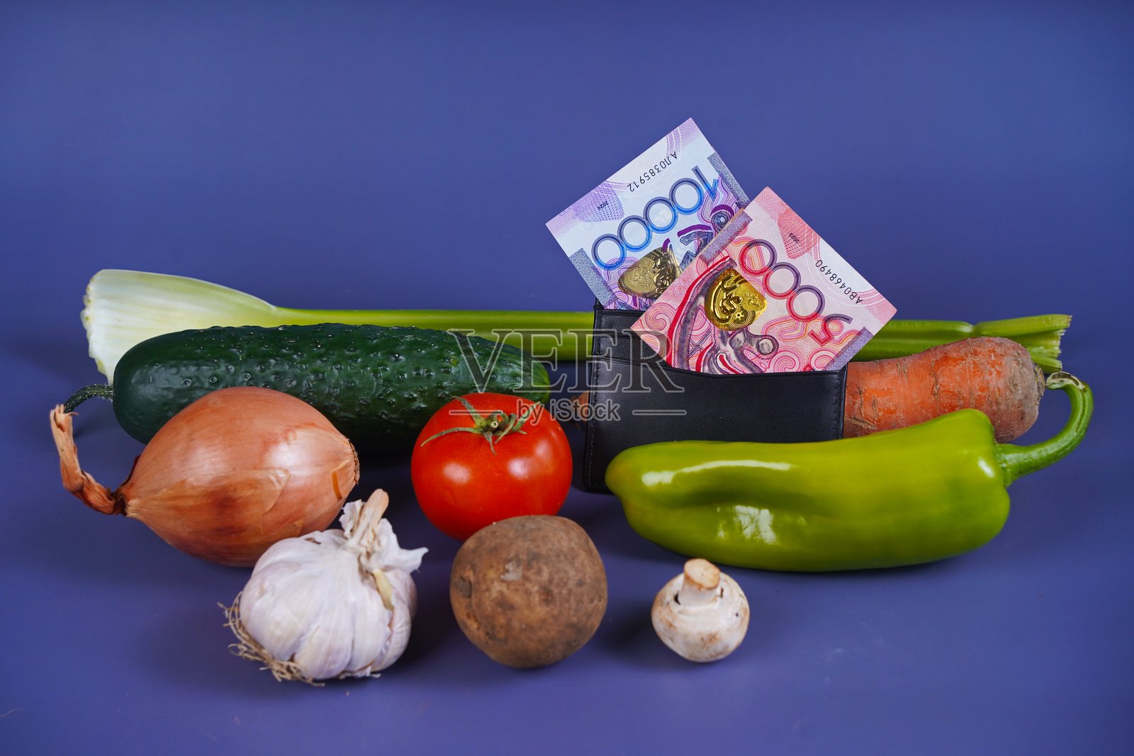 桌上摆放着不同面值的腾格和各种蔬菜:芹菜、胡萝卜、黄瓜、番茄、土豆、蘑菇、洋葱、大蒜、辣椒。照片摄影图片