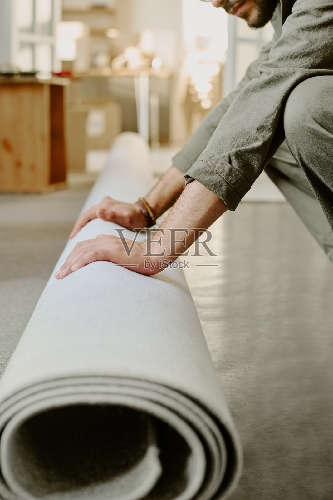 年轻男子搬入新公寓时卷地毯照片摄影图片