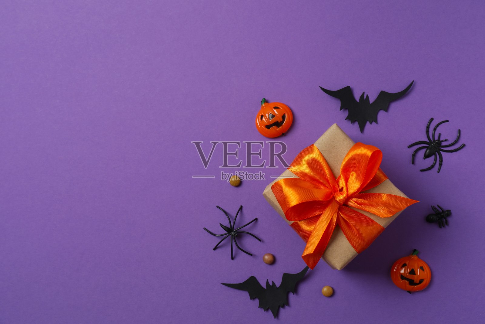 万圣节假期装饰品,包括礼品盒、南瓜、蜘蛛、蝙蝠,背景为彩色照片摄影图片